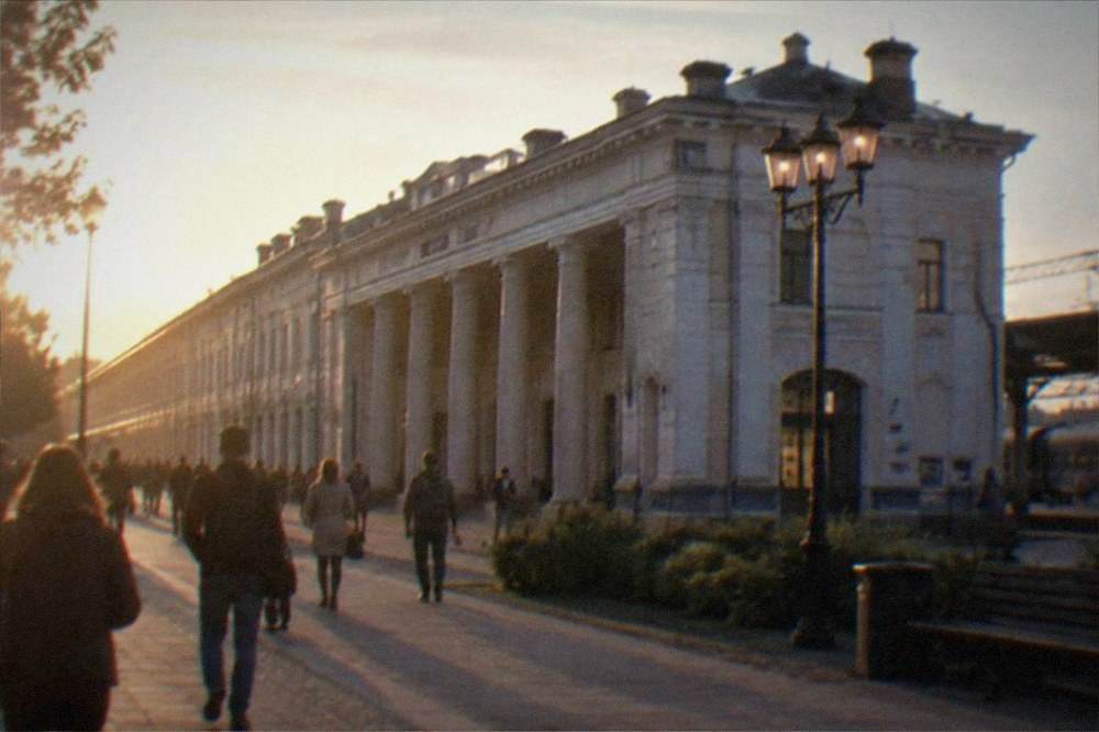 A lit historic city street at dusk with people walking to restaurants