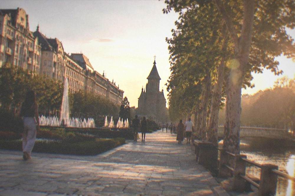 A tree-lined canal promenade at golden hour with people strolling