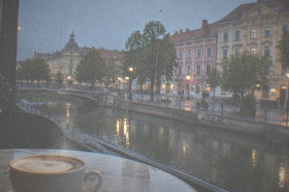 Steam rising from a cappuccino on a marble cafe table beside a rain-streaked window