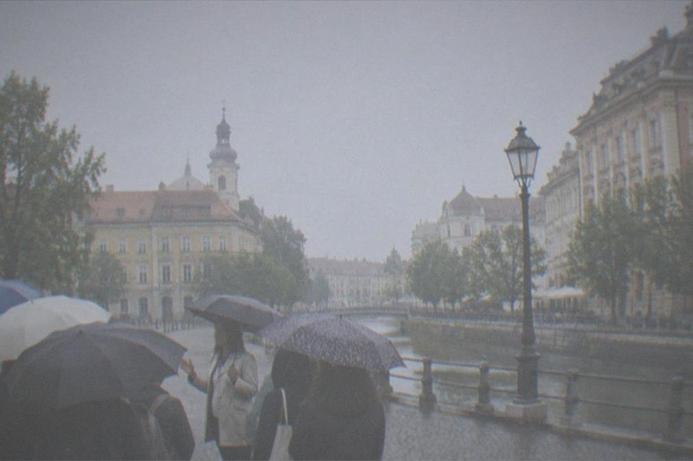 A tour guide speaking to a small group under umbrellas in a historic square
