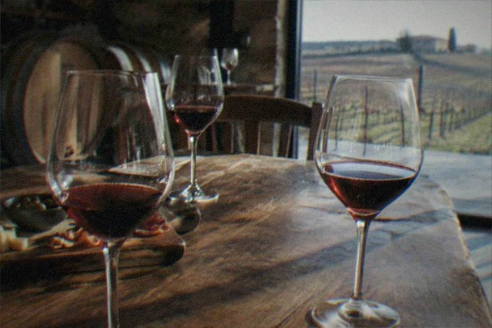 Wine glasses on a wooden tasting table inside a rustic winery cellar