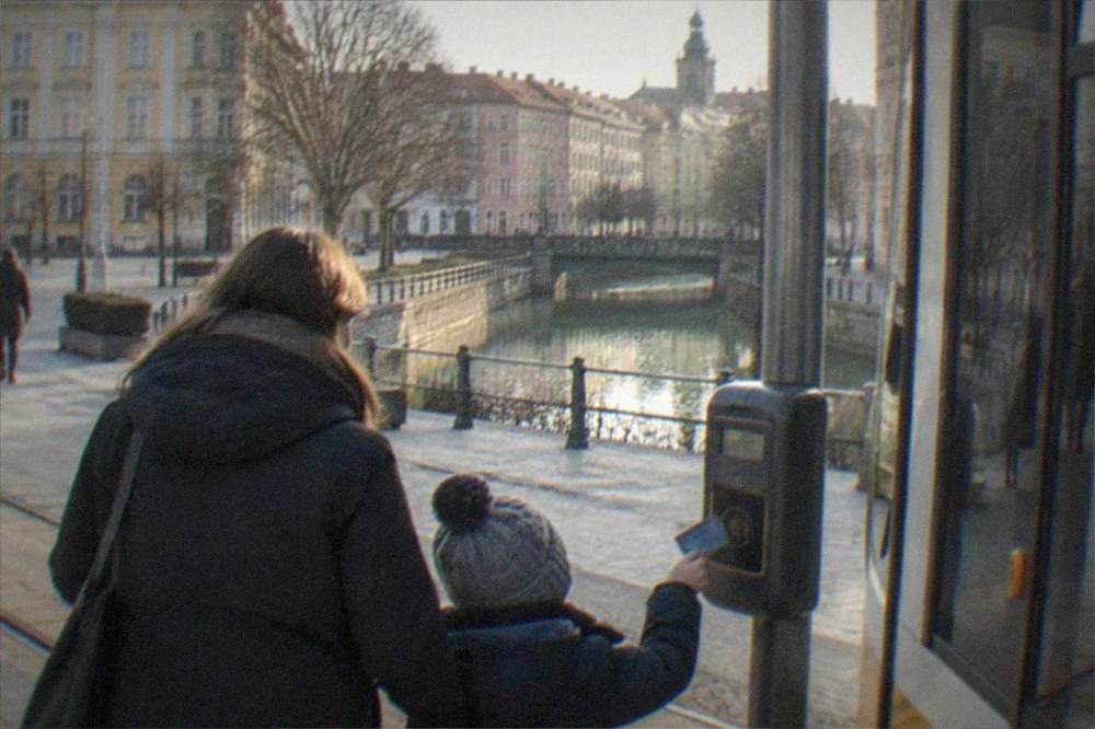 A parent and child tapping a contactless card on a tram ticket reader in Timisoara